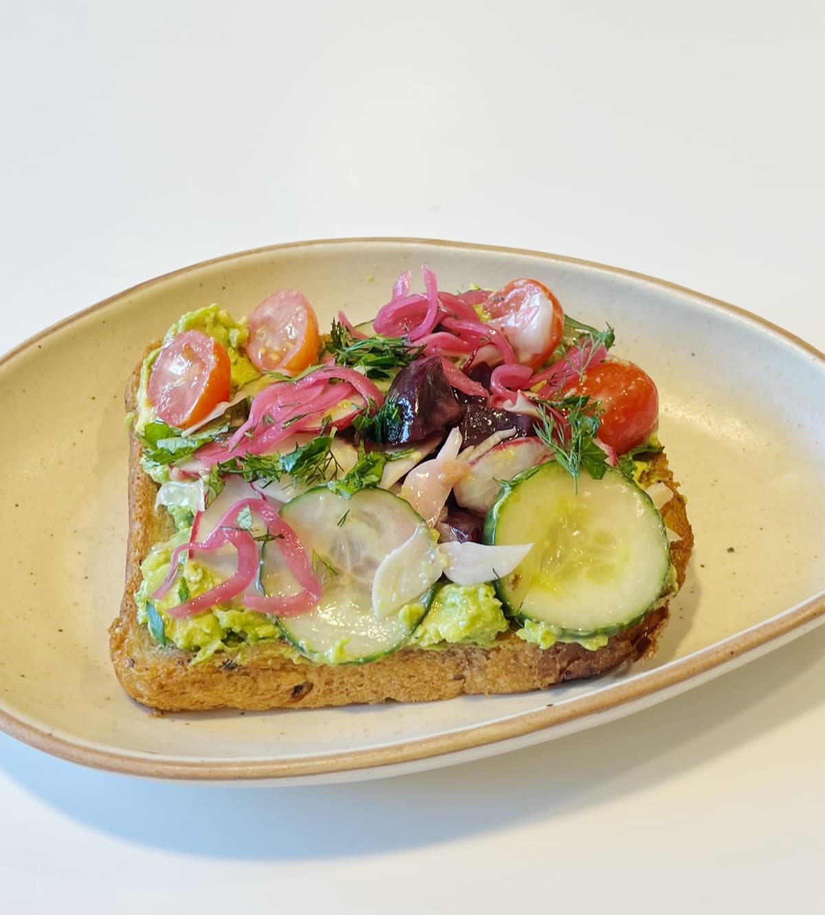 Avocado toast with pickled red onion, cherry tomatoes, herbs and cucumber